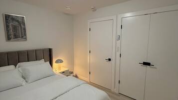 A bedroom with a bed, bedside table, lamp, and two wardrobes.