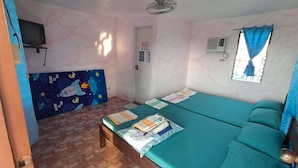 Une pièce comprenant un lit, une petite table, un téléviseur et une fenêtre avec des rideaux.