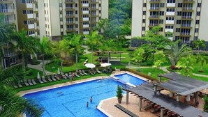 A hotel with a swimming pool surrounded by lush greenery and a covered outdoor seating area. - Jaco, Beautiful apartment just a few steps from the ocean, perfect for families. (Jacó)