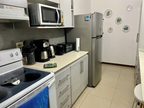 A kitchen with a microwave, coffee maker, toaster, refrigerator, and a stove. - Jaco, Beautiful apartment just a few steps from the ocean, perfect for families. (Jacó)