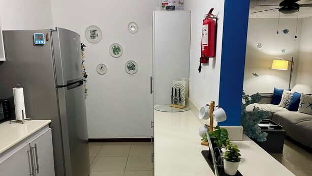 A modern kitchen with a refrigerator, stove, and microwave. There is a dining table with chairs and a potted plant. - Jaco, Beautiful apartment just a few steps from the ocean, perfect for families. (Jacó)