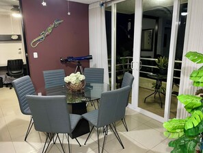 A dining area with a glass table surrounded by chairs, a telescope, and a decorative wall piece. - Jaco, Beautiful apartment just a few steps from the ocean, perfect for families. (Jacó)