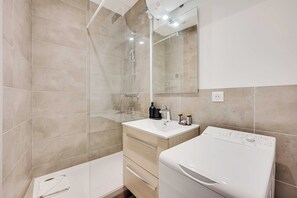 Ein modernes Badezimmer mit Dusche, Waschbecken und Spiegel.