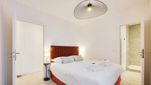 A hotel room with a bed, a bedside lamp, a door, and a shower area. - Cosy Appartement - 1bdr/4p - Boulogne Billancourt (Boulogne-Billancourt)