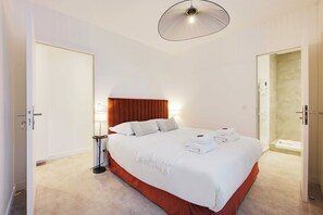 Ein Hotelzimmer mit Bett, Nachttischlampe, Tür und Duschbereich.