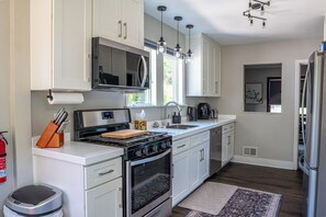 A modern kitchen with white cabinetry, stainless steel appliances, a gas stove, and a built-in oven.