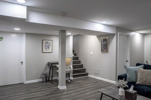 A modern living room with a staircase, a desk, and a sofa.