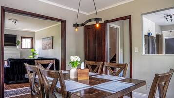 A dining area with a wooden table, chairs, and a vase with flowers.