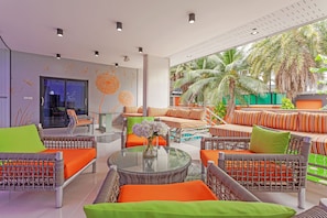 Eine moderne Lounge-Bereich im Freien mit Rattanmöbeln, einem Glastisch und Blick auf Palmen.