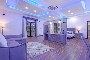 Ein modernes Schlafzimmer mit Sofa, Schminktisch mit Spiegel, Bett und Schreibtisch.