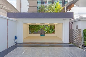 A modern building with a flat roof, a gated entrance, and a small pool area with plants. - Royal Grand - Luxury 4-bedroom villa for 8 people in Pattaya (Bang Lamung)