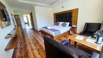 A hotel room with a bed, a desk, a chair, a television, and a ceiling fan.