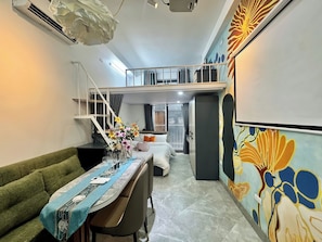 A hotel room with a dining area, a bed with a view, a staircase, and a colorful wall mural.