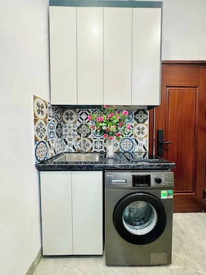 A compact kitchen with a washing machine, a sink, and a cabinet.