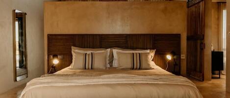 A bedroom with a large bed, wooden headboard, and a sloped ceiling.