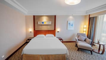 Habitación de hotel con una cama grande, una silla, una mesita y un cuadro en la pared.