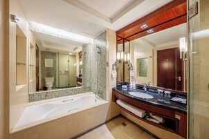 Un baño moderno con una bañera grande, un lavamanos doble y una zona de ducha con mampara de vidrio.