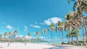 A beach with palm trees, a clear sky, and a distant mountain. - Cute Studio in the center of Waikīkī with Parking (Honolulu)