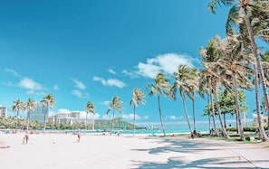 A beach with palm trees, a clear sky, and a distant mountain. - Cute Studio in the center of Waikīkī with Parking (Honolulu)