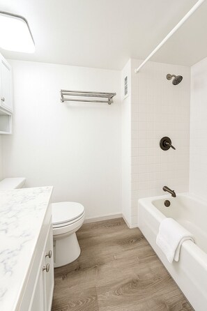 A bathroom with a toilet, a marble sink, a bathtub, and a shower. - Cute Studio in the center of Waikīkī with Parking (Honolulu)