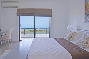 Ein Hotelzimmer mit Bett, Schreibtisch, Stuhl und einem großen Fenster mit Meerblick.