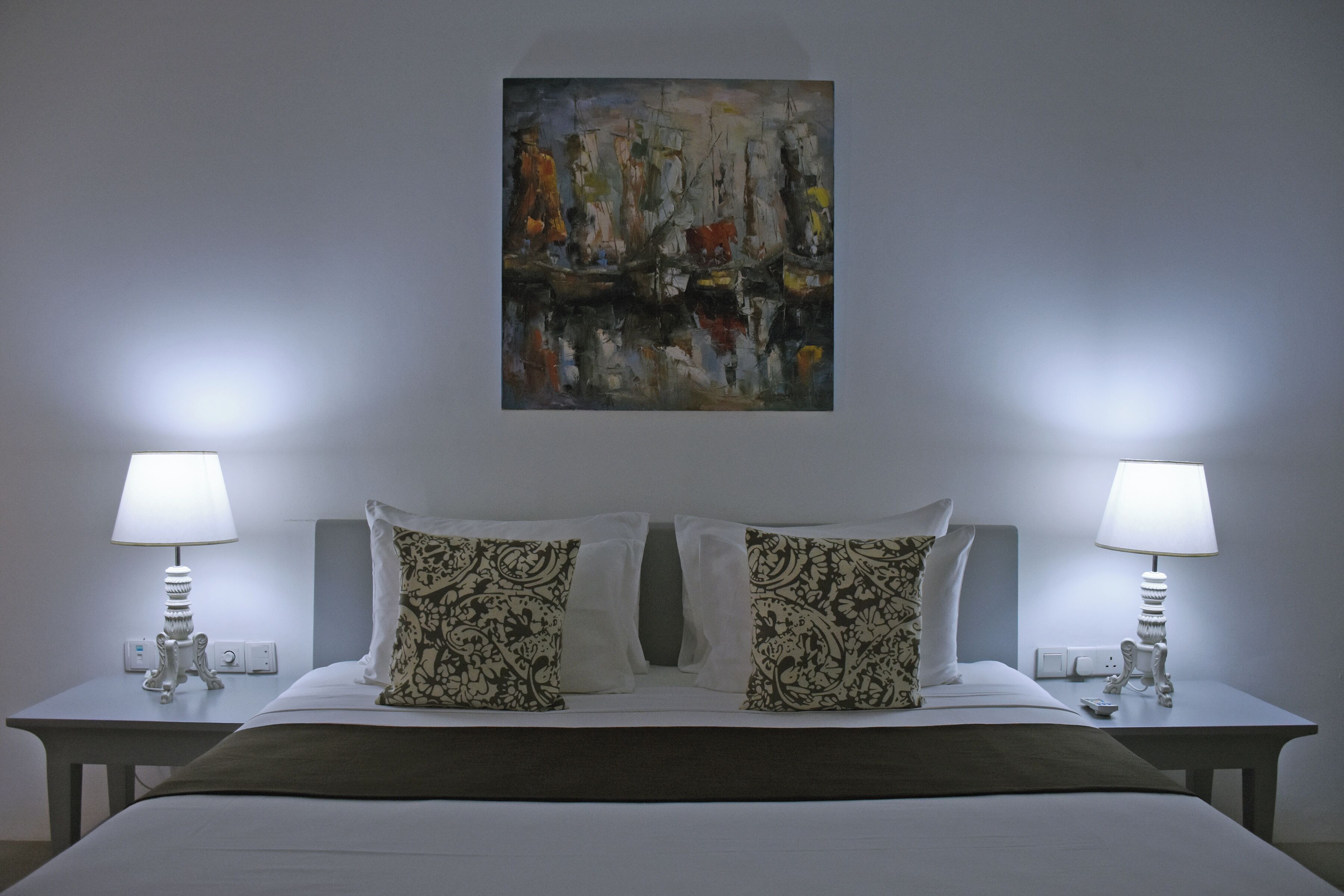 Habitació d'hotel amb un llit gran, dues tauletes de nit, dues làmpades i un quadre a la paret.
