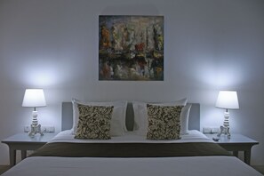 Een hotelkamer met een groot bed, twee nachtkastjes, twee lampen en een schilderij aan de muur.