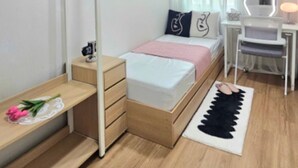 Moderni makuuhuone, jossa on sänky, yöpöytä, työpöytä, tuoli ja peili.