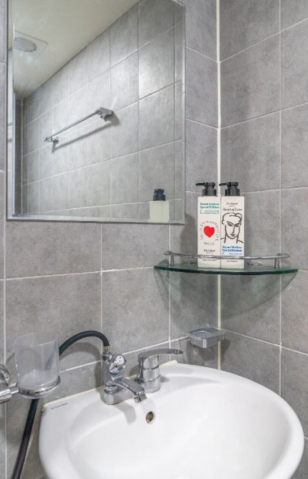 A bathroom with a white sink, a glass shelf, and a mirror.