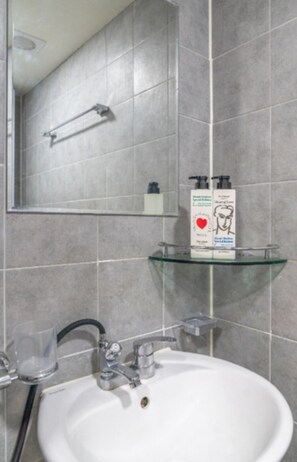 Ein Badezimmer mit einem weißen Waschbecken, einer Glasablage und einem Spiegel.
