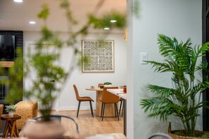 A modern interior with a dining area, a large plant, and a wall-mounted artwork.