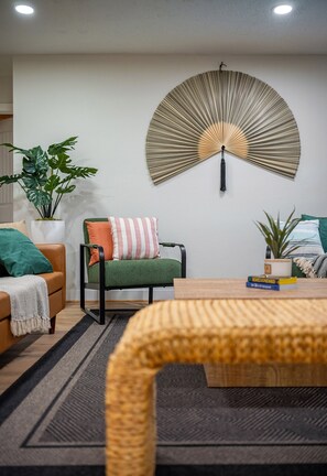 A modern living room with a sofa, a chair, a coffee table, and a decorative wall piece.