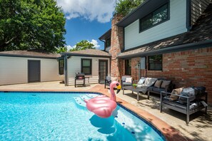 A backyard with a swimming pool, a brick wall, and outdoor furniture. - Cozy 5-bedroom house in adorable Spring with pool (Spring)