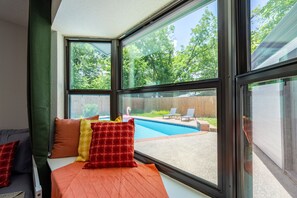 A room with a large window overlooking a backyard with a swimming pool and lounge chairs. - Cozy 5-bedroom house in adorable Spring with pool (Spring)