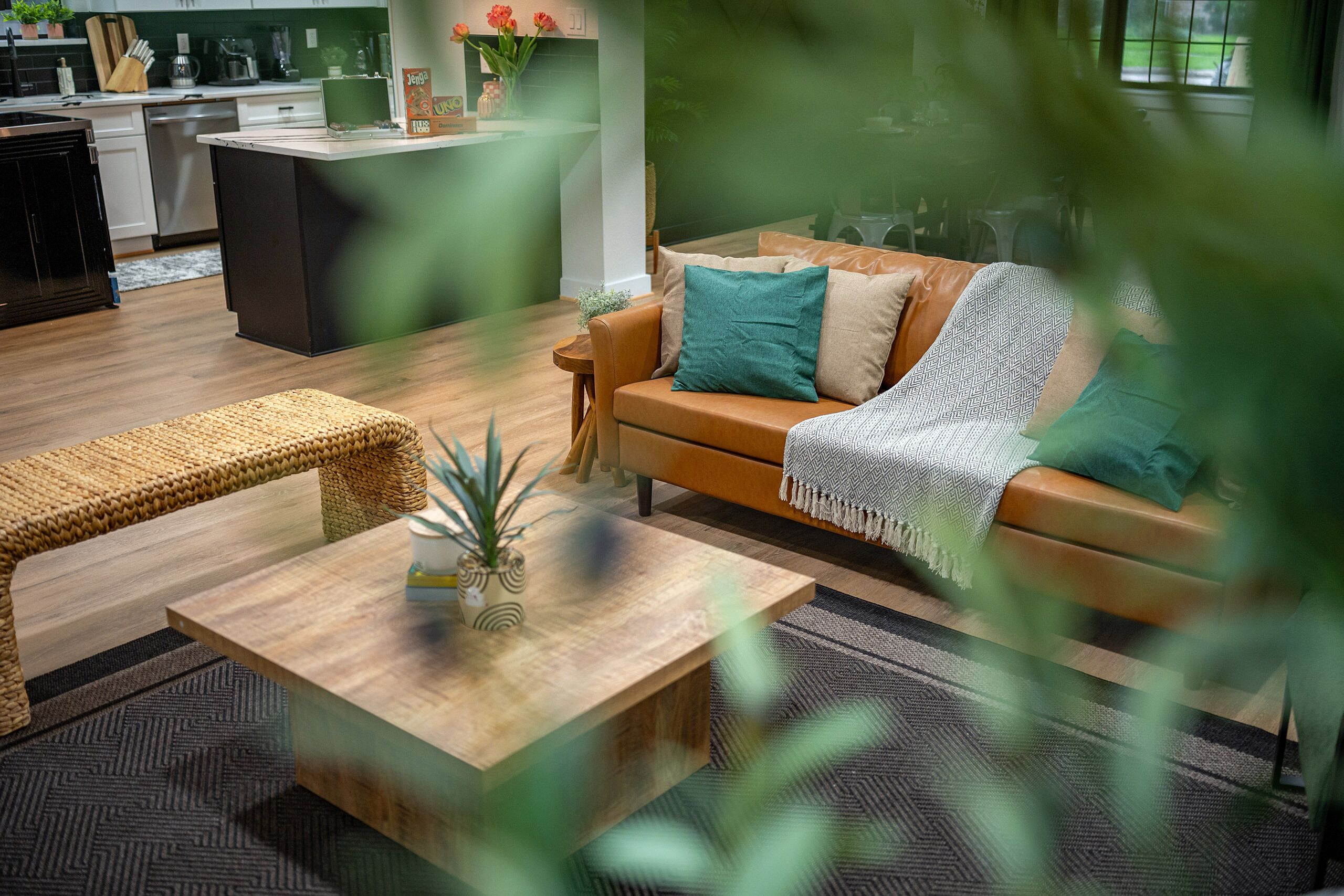 Una sala de estar moderna con sofá, mesa de centro y comedor, con una cocina al fondo.