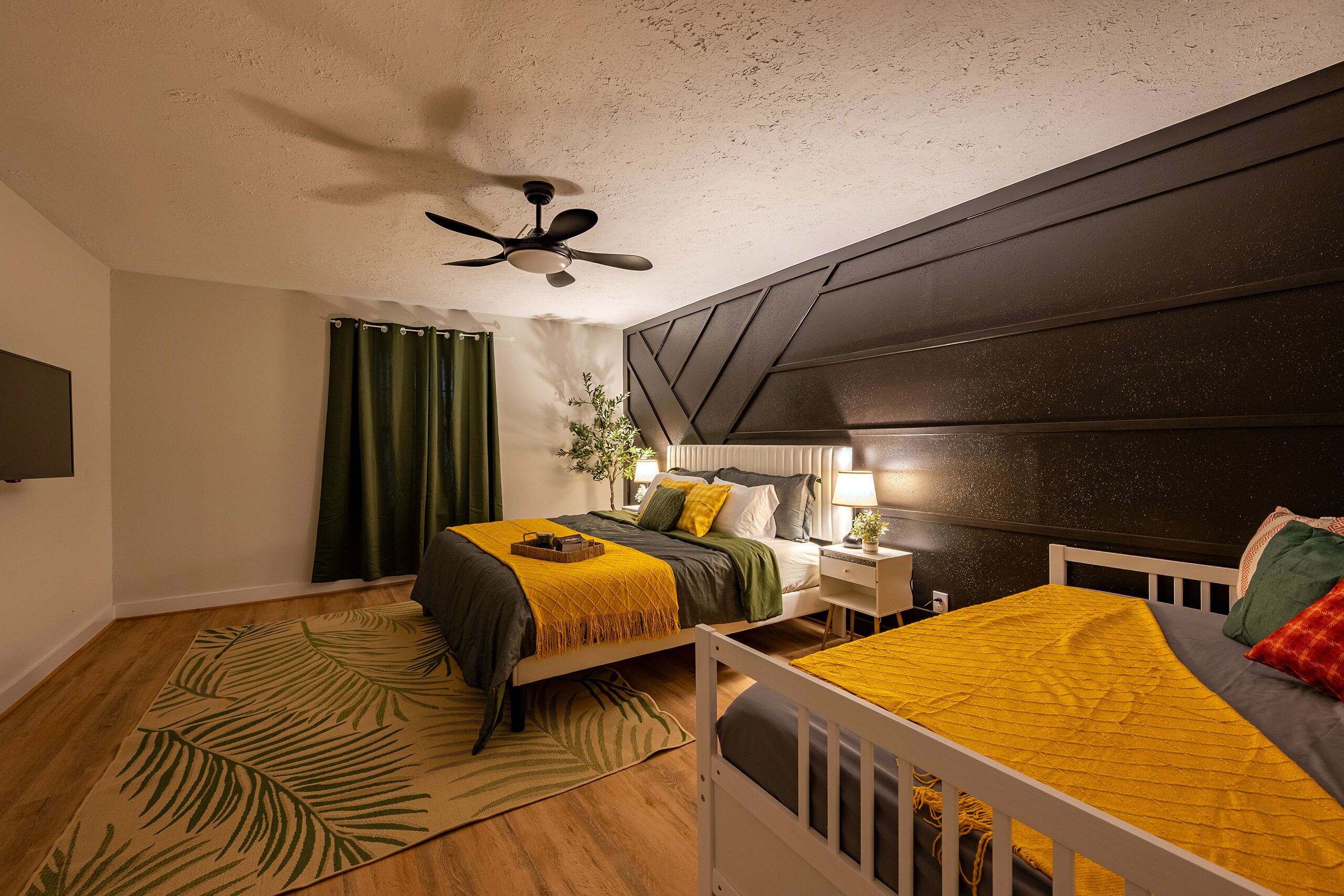 A bedroom with a bed, bedside table, lamp, and a ceiling fan.