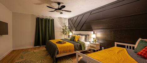 A bedroom with a bed, bedside table, lamp, and a ceiling fan.