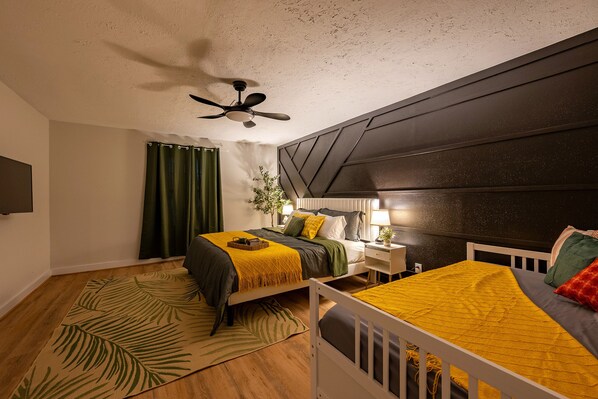 A bedroom with a bed, bedside table, lamp, and a ceiling fan.