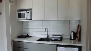 Cocina compacta con microondas, fregadero y refrigerador pequeño.