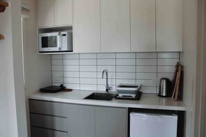 Eine kleine Küche mit Mikrowelle, Spüle und einem Kühlschrank.