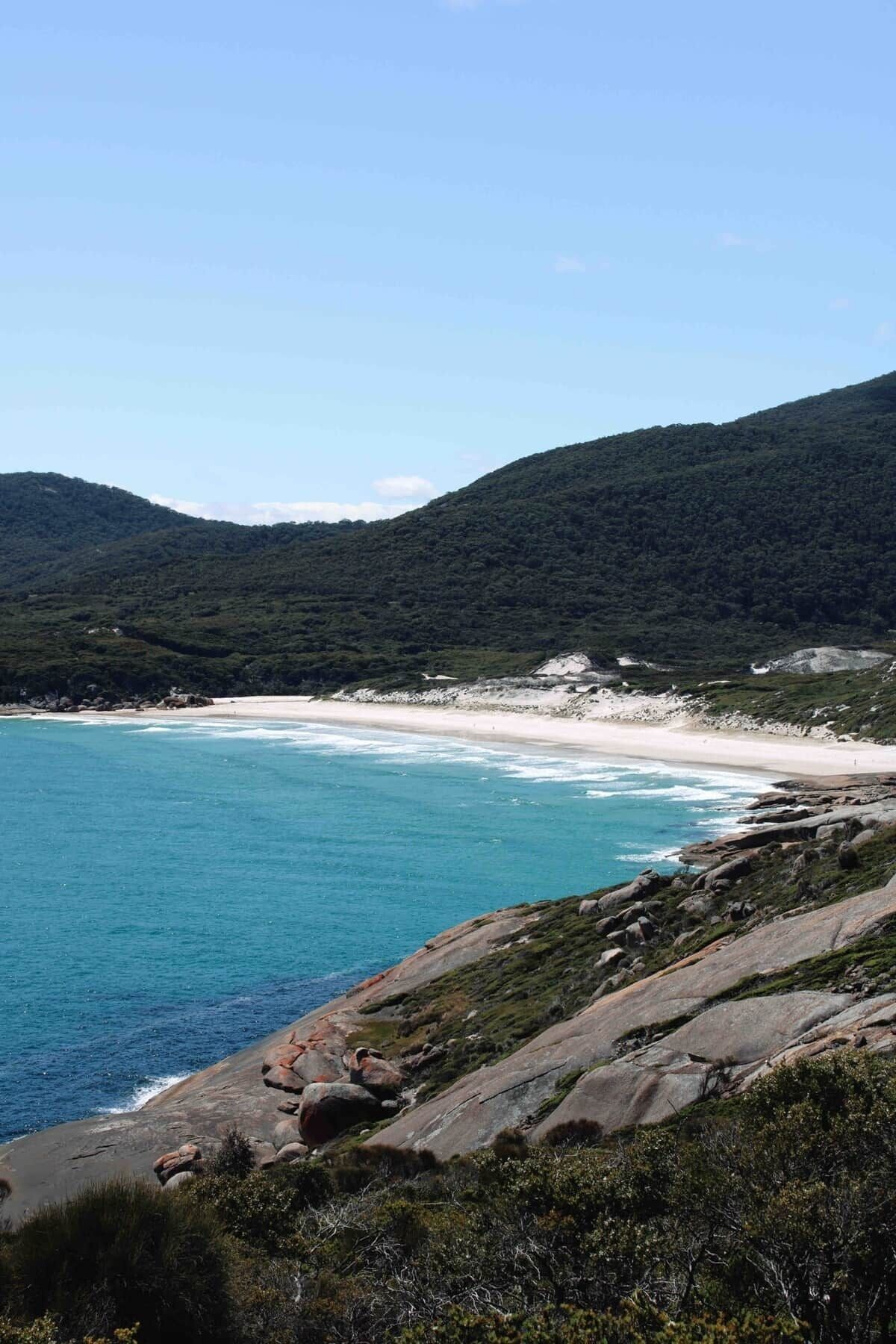 Un paisaje costero con playa y terreno rocoso.