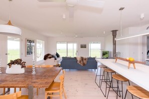 Une cuisine moderne dotée d’un îlot central, de tabourets de bar et d’un coin repas avec des chaises.