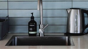 Eine Spüle mit modernem Wasserhahn, eine Handseifen-Spender und ein Edelstahl-Wasserkocher auf der Arbeitsplatte.