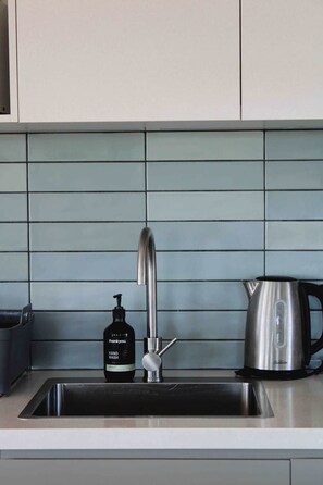 A kitchen sink with a modern faucet, a hand soap dispenser, and a stainless steel kettle on the countertop. - The Yanakie House - Wilsons Promontory (Yanakie)