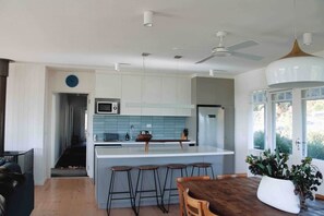 Uma cozinha moderna com ilha central, banquetas de bar e uma mesa de jantar.