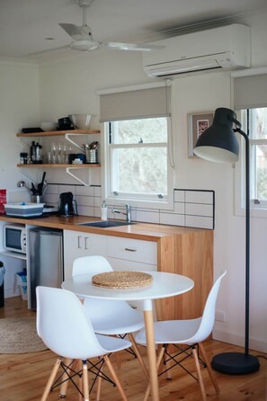 Una cucina moderna con isola centrale, sedie bianche, un tavolo rotondo e una lampada da terra.