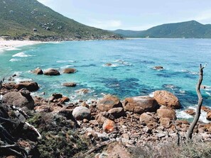 A rocky shoreline with clear blue water and distant mountains. - Wattle - The Yanakie House - Wilsons Promontory (Yanakie)