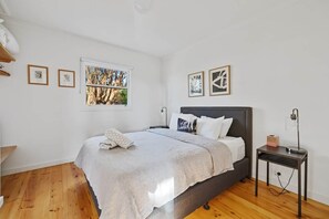 A bedroom with a bed, a bedside table, a window, and wall art. - Wattle - The Yanakie House - Wilsons Promontory (Yanakie)