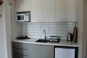 A compact kitchen with a microwave, sink, and a small refrigerator.