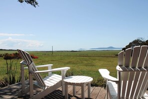 Two Adirondack chairs on a wooden deck overlooking a grassy field with a distant mountain range. - Bluegum - The Yanakie House - Wilsons Promontory (Yanakie)